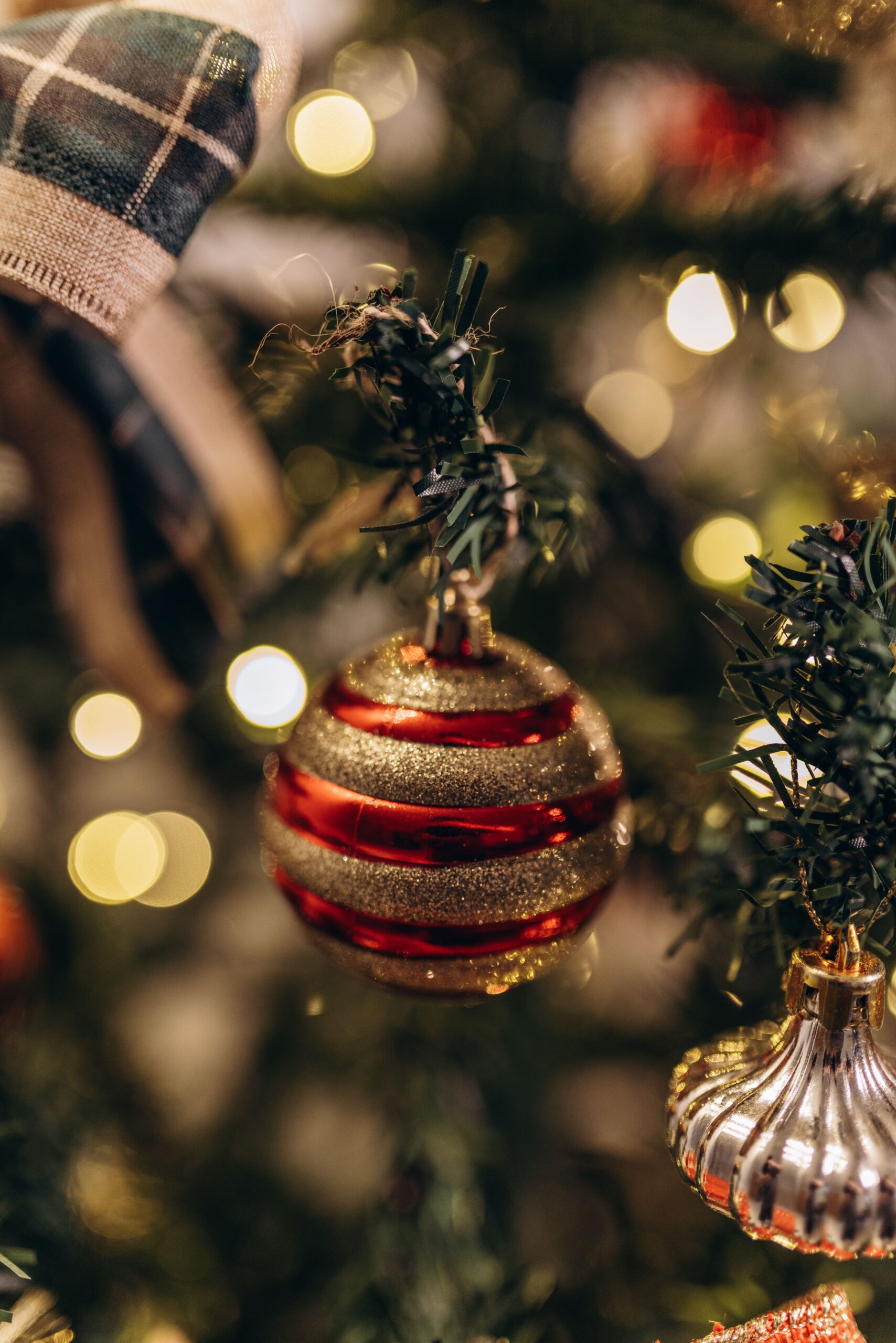 Close-up of a glittering red and gold bauble on a decorated Christmas tree.